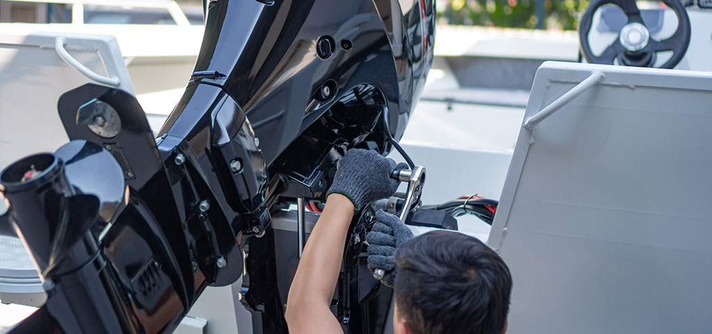 Il meccanico sta installando il motore del motoscafo, un nuovo motore su una barca in alluminio.