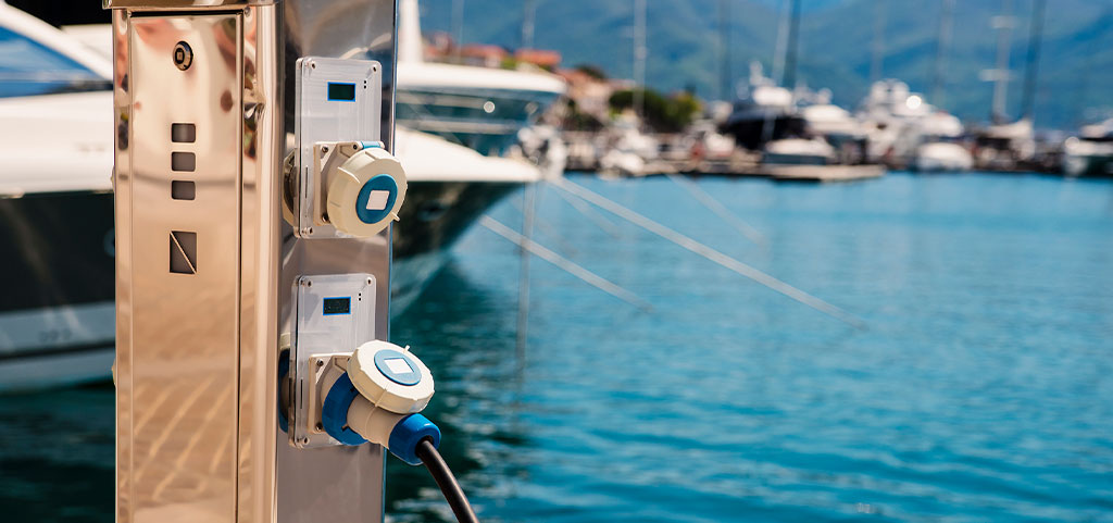 Stazione di ricarica per barche. Prese elettriche per la ricarica delle navi nel porto su un molo vicino alla costa del mare. Ricarica dello yacht dalla centrale elettrica nel porto turistico. Piedistallo marino intelligente.